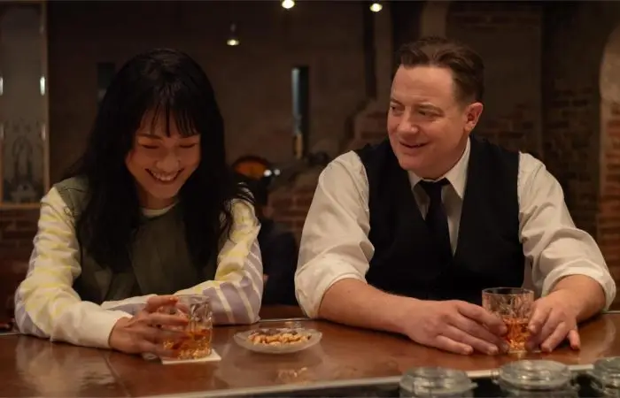 Brendan Fraser și Takehiro Hira din filmul Familie de inchiriat stau la bar și discută